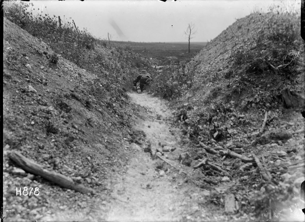 A New Zealand runner crawls through a front line trench trying to avoid enemy machine gun fire. Gommecourt Wood, France, 10 August 1918.